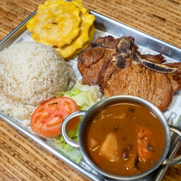Casa Borinquen's Puerto Rican meal with pork chops, rice, plantains, salad, and a side of soup.